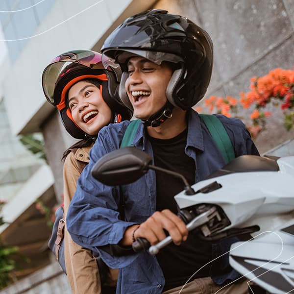 Casal sorrindo em uma moto enquanto passeiam pela cidade
