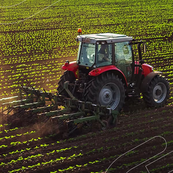 Trator puxando uma semeadora através de um campo sob a luz do sol
