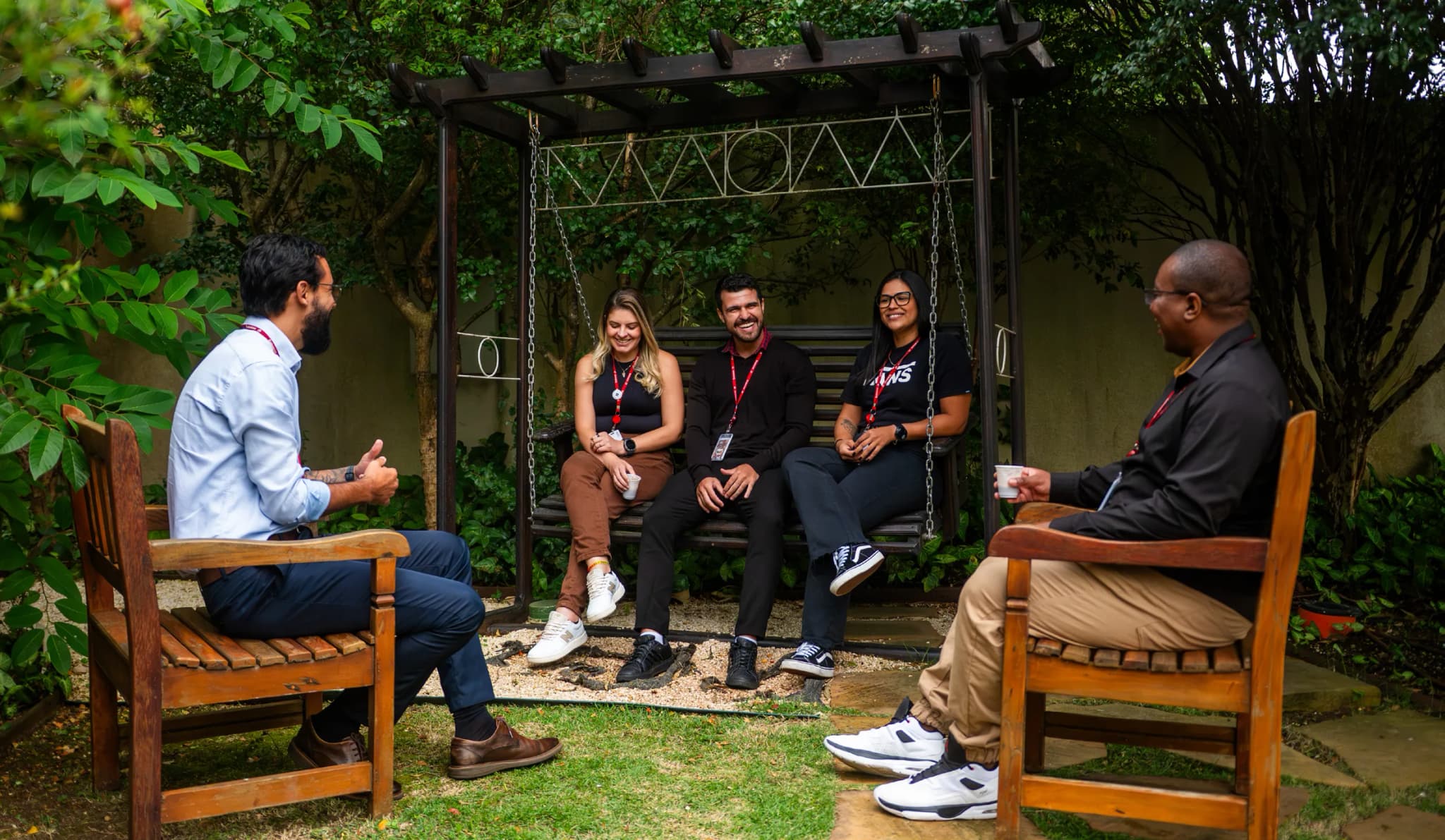Nossas Pessoas — grupo diverso de colaboradores conversando no jardim